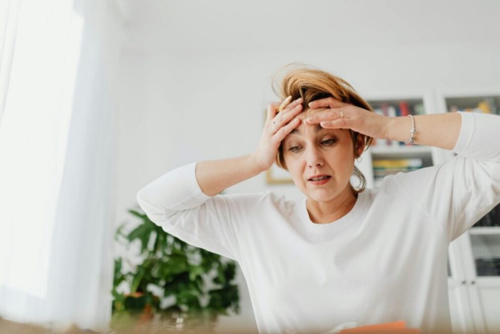 Worried woman holding her head indoors, expressing stress linked to OCD checking behaviours