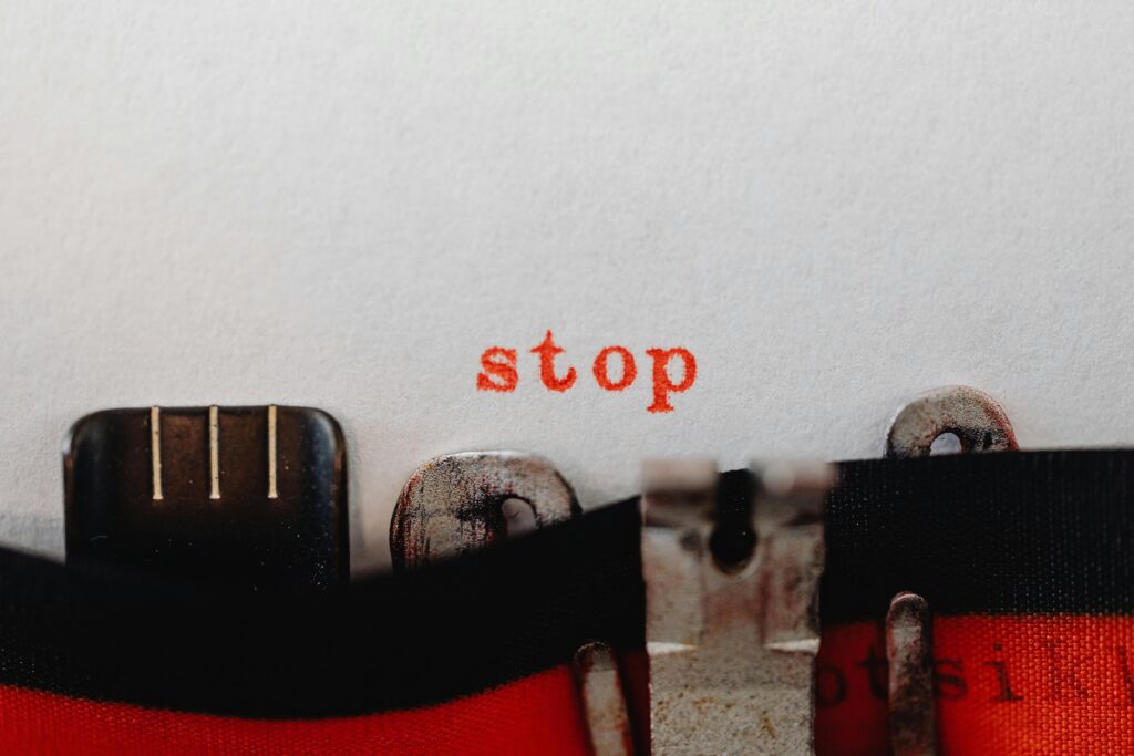 Red typewriter typing the word STOP, symbolising the urge to suppress intrusive thoughts — a pattern that backfires in OCD and anxiety