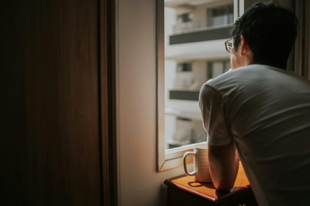 A person sitting in quiet contemplation, seen from behind against soft natural light, representing the uncertainty and distress of health anxiety or OCD