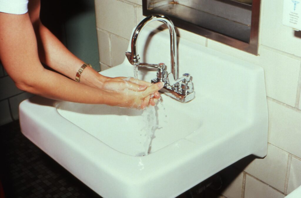 A person washing their hands carefully at a white sink, illustrating the compulsive handwashing behaviour common in contamination OCD